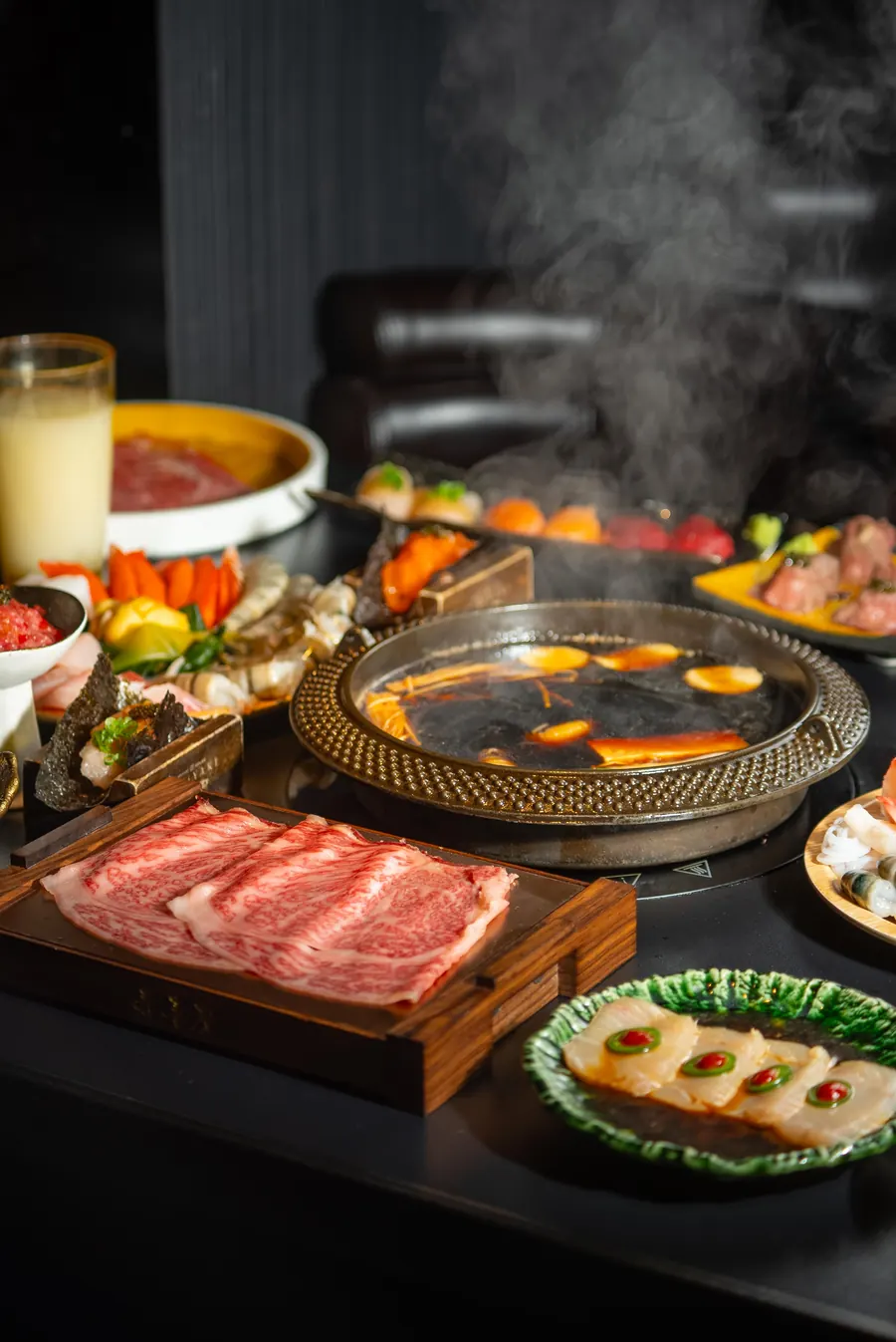 A full sukiyaki table with wagyu, seafood and sides